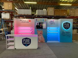 RENTAL: Gravitee Panel System Design with Large Monitor Mount, 50" Monitor, (6) 52" Wide x 12" Deep White Laminated Shelves with Down Lighting, (2) LED Arm Lights, RE-1595 White Laminated Reception Counter with Recessed RGB Accent Lighting, Custom Open Sh